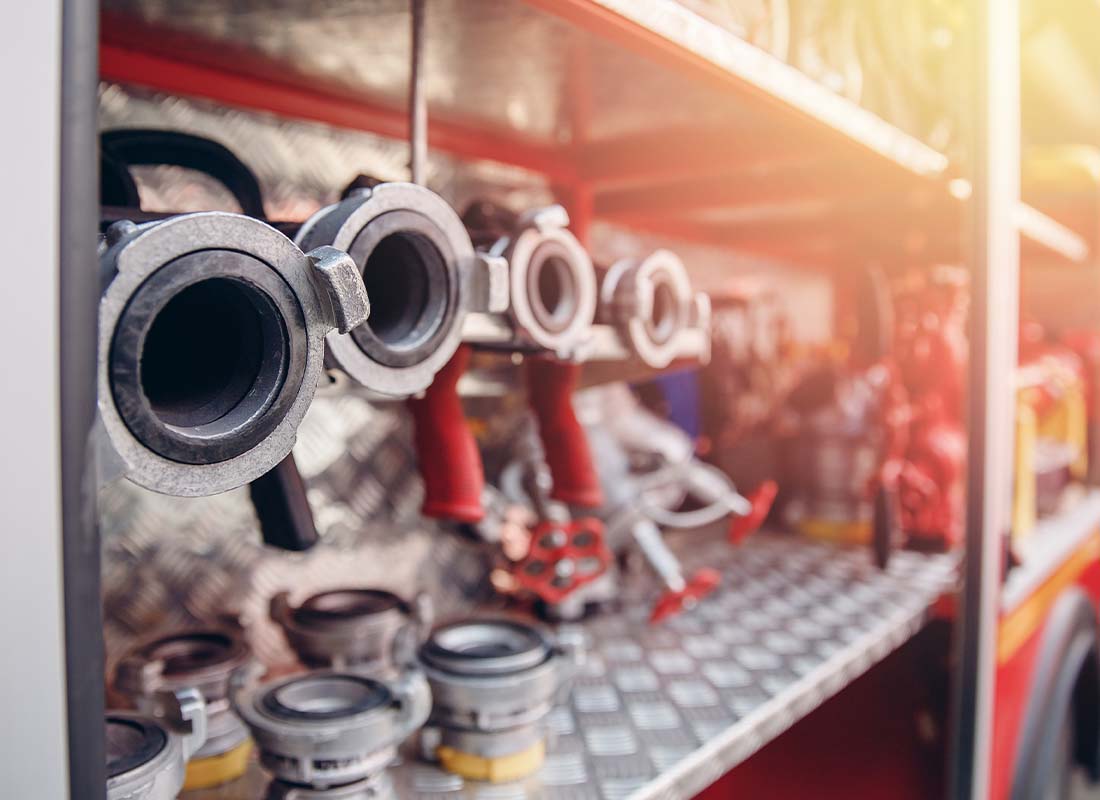 Fire Department Insurance - Close-up Focus of Fire Hoses in a Red Fire Truck Dug Out and Ready for Use With the Rest of Truck Blurred