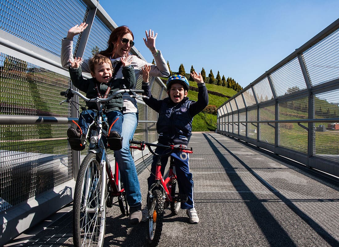 Employee Benefits - Mother and Her Two Young Sons Riding a Bike Over a Bridge